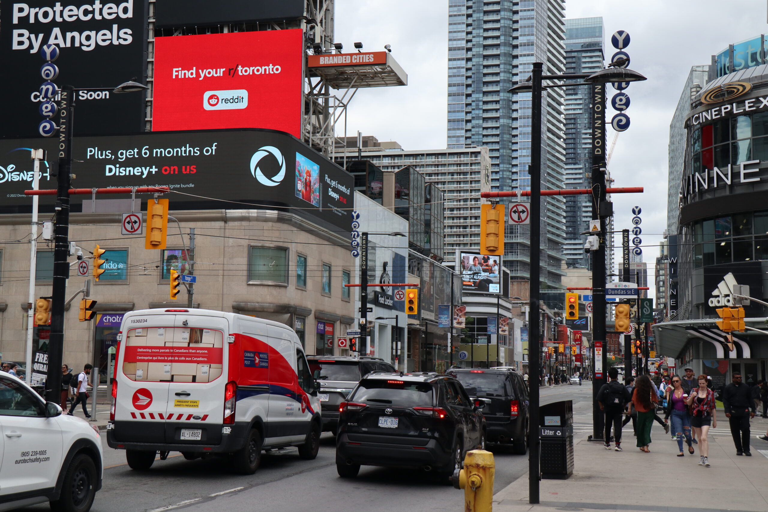 A busy intersection showing a lot of cars and people walking.